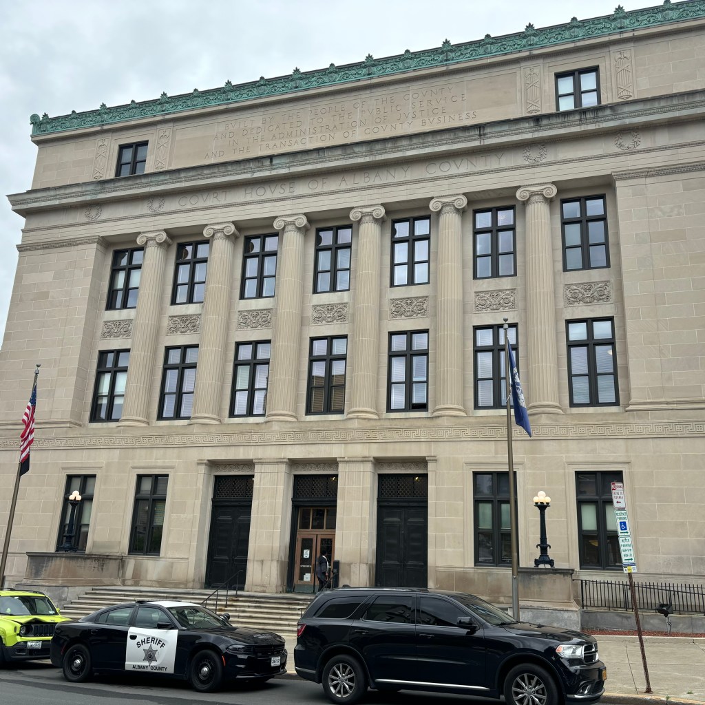 Exterior of Albany County Court House with parked police vehicles in front.